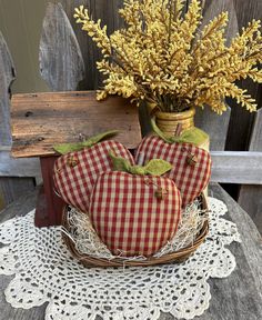 two apples sitting in a basket on top of a table next to a vase with yellow flowers