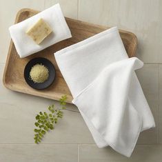 a wooden tray topped with white towels next to a black plate