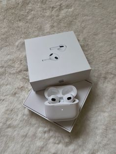 an apple airpods sitting in a white box on top of a fluffy carpeted floor