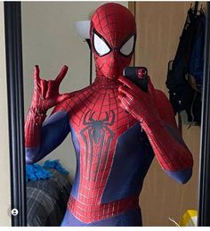 a spider man standing in front of a mirror holding his hands up to the side