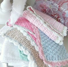 a stack of crocheted towels sitting on top of a table next to a vase