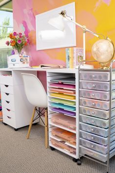 a desk with many drawers and a lamp on it in front of a colorful wall