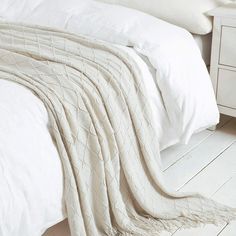 an unmade bed with white sheets and pillows