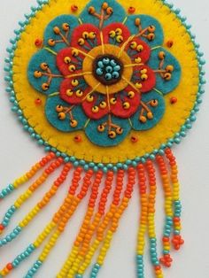 a colorful piece of art made out of beads and bead work on a white surface