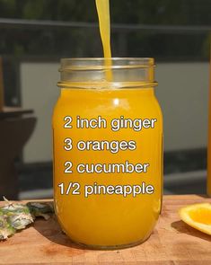 a jar filled with orange juice sitting on top of a wooden table