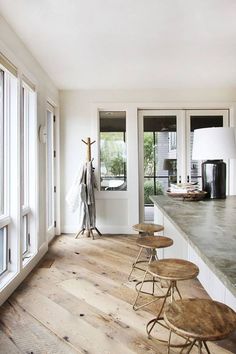 an empty kitchen with stools on the counter and large windows looking out onto the back yard