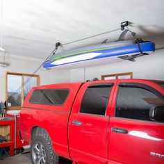 a red pick up truck in a garage with a surfboard hanging from the ceiling