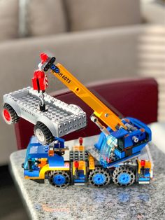 a toy truck with a crane on top of it sitting on a table next to a couch