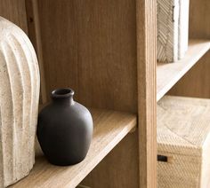 a black vase sitting on top of a wooden shelf