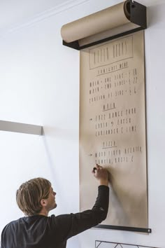 a man writing on a wall with a roll of paper