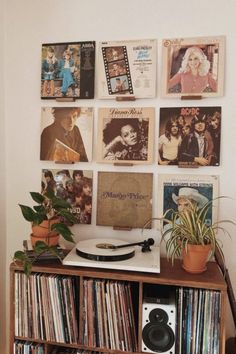 a record player sitting on top of a wooden shelf next to a wall filled with records