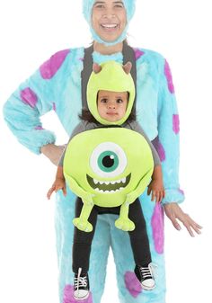 a man in a costume holding a child wearing a monster costume on his chest and smiling at the camera