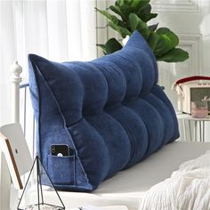 a large blue pillow sitting on top of a bed next to a white table and chair