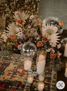 a table topped with lots of candles and vases filled with different types of flowers