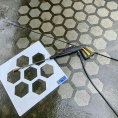 a tool laying on the ground next to a hole in the floor with holes cut into it