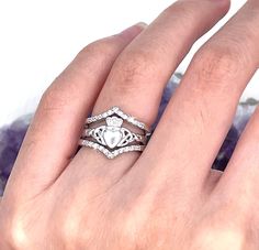 a woman's hand with two wedding rings on top of her finger and the other hand holding an engagement ring