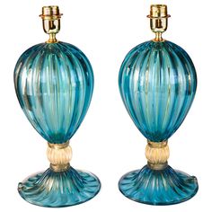 two blue glass vases sitting next to each other