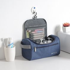 a blue toiletry bag sitting on top of a counter next to a toothbrush holder