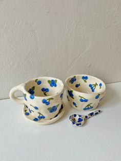 two cups and saucers with blue flowers on them are sitting next to each other