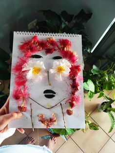 a person holding up a piece of paper with flowers on it and a woman's face