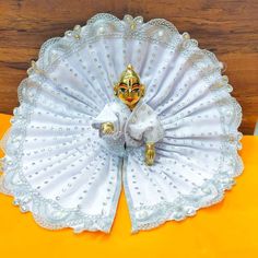 a decorative white fan sitting on top of a wooden table next to an orange pillow