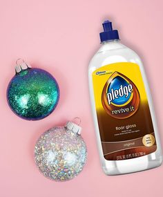 a bottle of deodorant next to a christmas ornament on a pink background