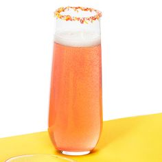 a glass filled with pink liquid sitting on top of a yellow table next to a plate