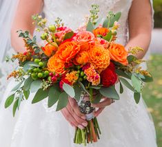 a bride holding a bouquet of orange and red flowers