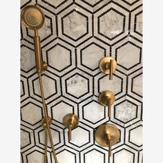 the shower head and handset are gold in color, with hexagonal tiles on the wall