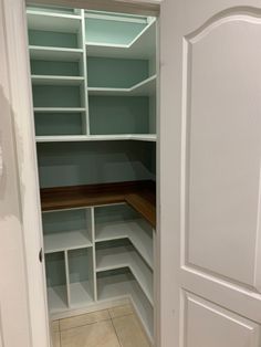 an empty walk in closet with white shelves