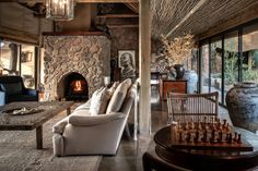 a living room filled with furniture and a fire place next to a stone wall covered in windows