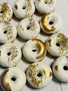 white and gold donuts with sprinkles are arranged in a circle on a table