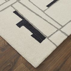 a white rug with black and grey designs on the bottom, along with wood flooring