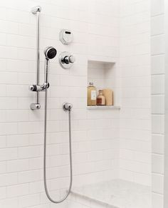 the shower head and handset are connected to the faucet in this white tiled bathroom