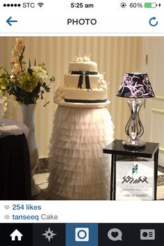 two tiered wedding cakes sitting on top of a table next to vases with flowers