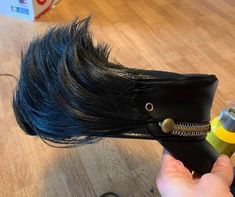 a person is using a hair dryer on a horse's head with long black hair