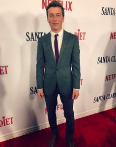 a man in a suit and tie standing on a red carpet