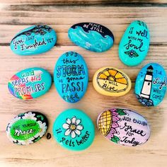 painted rocks with words on them sitting on top of a wooden table next to each other