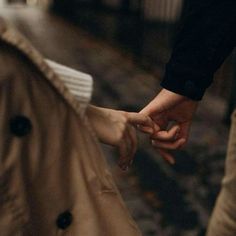 two people holding hands while walking down the street