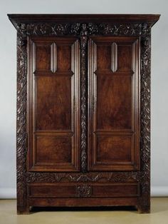 an antique wooden armoire with carvings on the front and sides, in dark wood