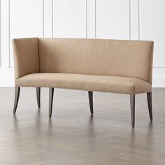 a beige bench sitting on top of a hard wood floor next to a white wall