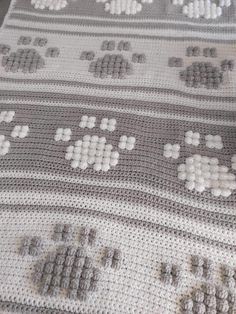 a crocheted blanket with white and gray designs