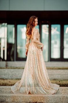 a woman in a gold dress is standing on the sidewalk and looking off into the distance