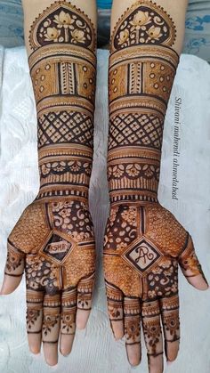 two hands with henna tattoos on them, one is showing the intricate design and the other has geometric designs