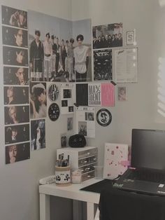 a laptop computer sitting on top of a desk next to a wall covered in pictures