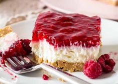 a piece of cheesecake on a plate with raspberry sauce and a fork