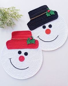 two crocheted snowmen with hats on their heads