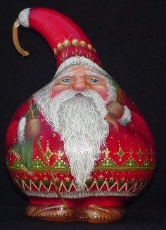 a red santa clause figurine sitting on top of a black surface with gold trimmings