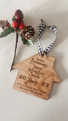 a wooden house ornament with pine cones, berries and ribbon hanging from it