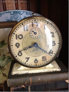 an old clock sitting on top of a stack of books